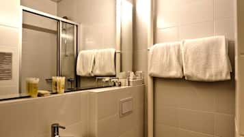 Un baño pequeño con lavamanos, inodoro y espejo. Hay toallas colgadas en la pared.