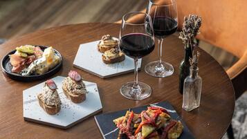 Una mesa de madera redonda con varios alimentos y copas de vino.