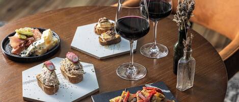 A round wooden table with various food items and wine glasses.