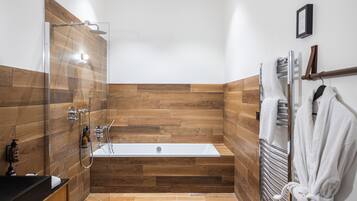 A modern bathroom with a wooden wall panel design, a bathtub, a shower area, and a towel rack with a robe.