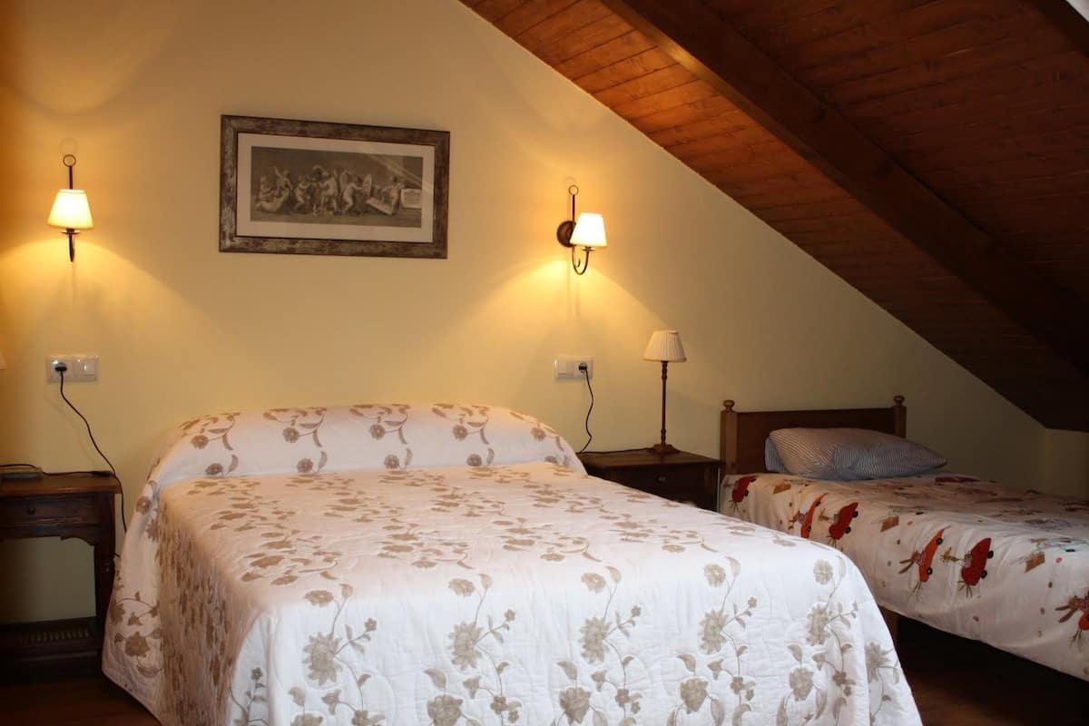Ein Schlafzimmer mit zwei Betten, einer Holzbalkendecke und Wandleuchten.