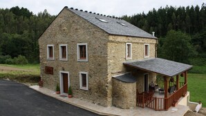 A stone house with a balcony and a small porch. - Casa Berbesa (Castropol)