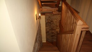 A wooden staircase with a stone wall behind it. - Casa Berbesa (Castropol)
