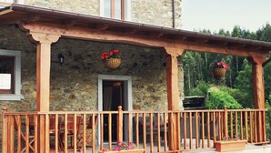 A stone building with a wooden balcony and flower planters. - Casa Berbesa (Castropol)