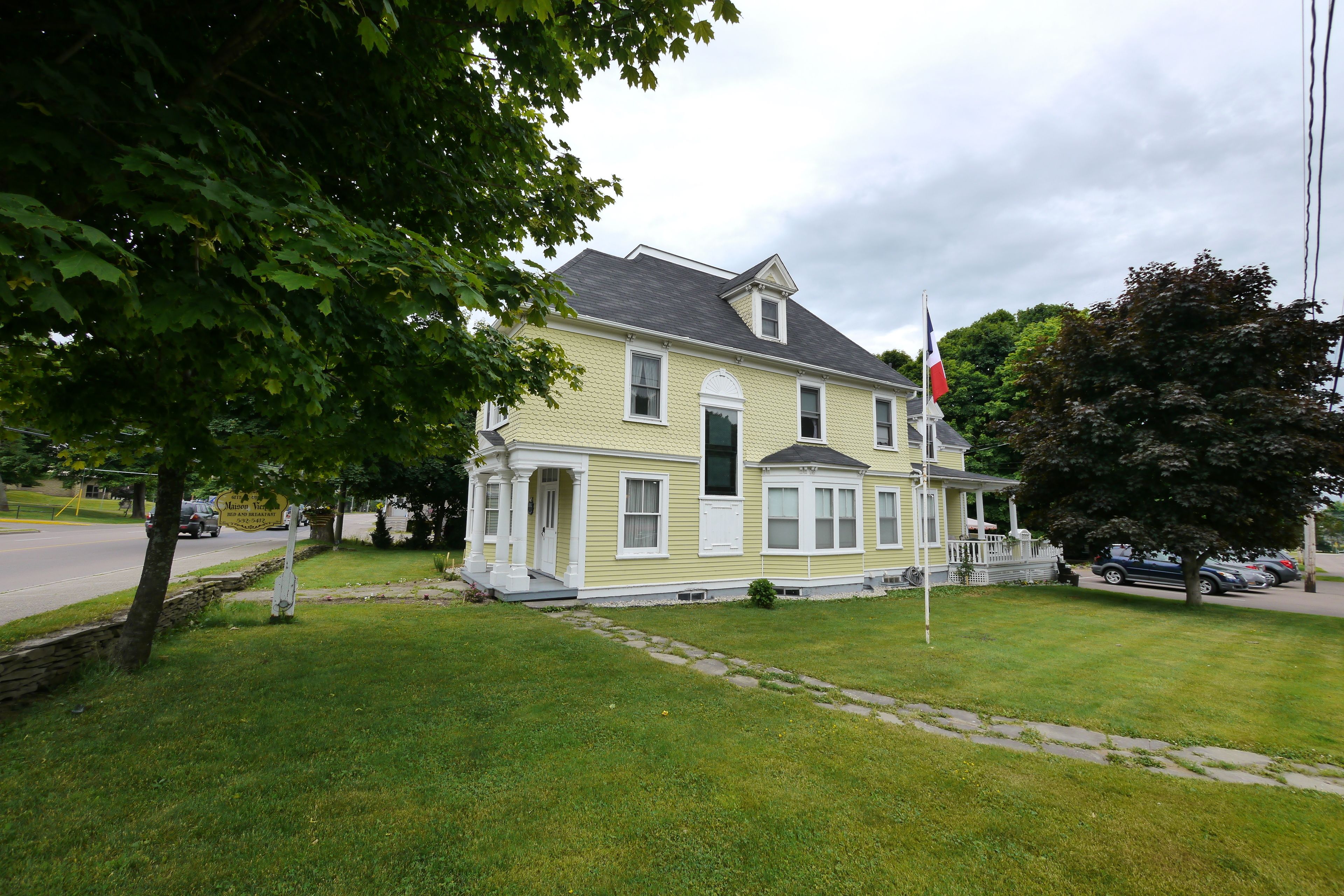 A two-story house with a porch, a garage, and a flagpole.