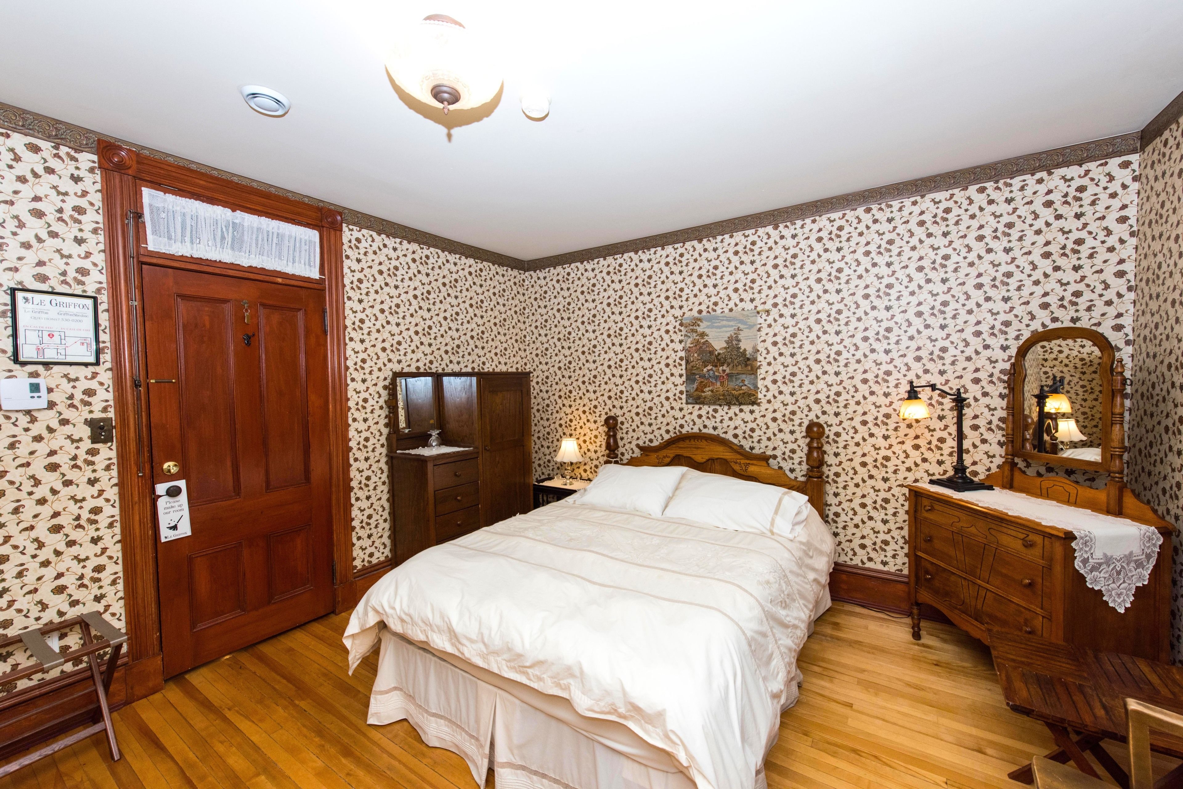 Une chambre à coucher avec un lit en bois, une commode, une table de chevet et un miroir.