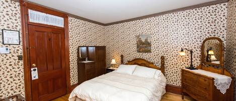 Une chambre à coucher avec un lit en bois, une commode, une table de chevet et un miroir.