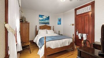 A bedroom with a wooden bed, a nightstand, a chair, a desk, and a wardrobe.