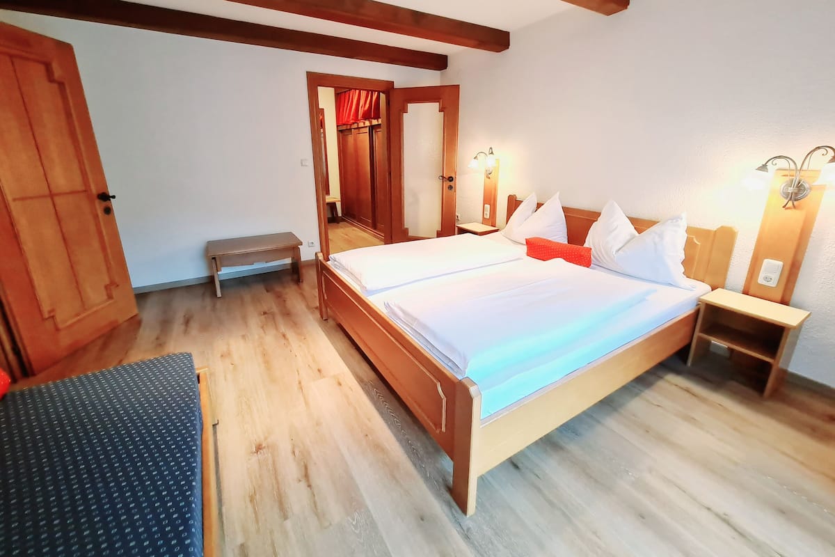A bedroom with a wooden bed, bedside tables, a bench, and a wardrobe.