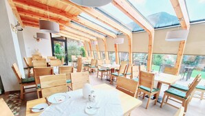 Un restaurante con mobiliario de madera y techo de cristal, que ofrece vistas al exterior.
