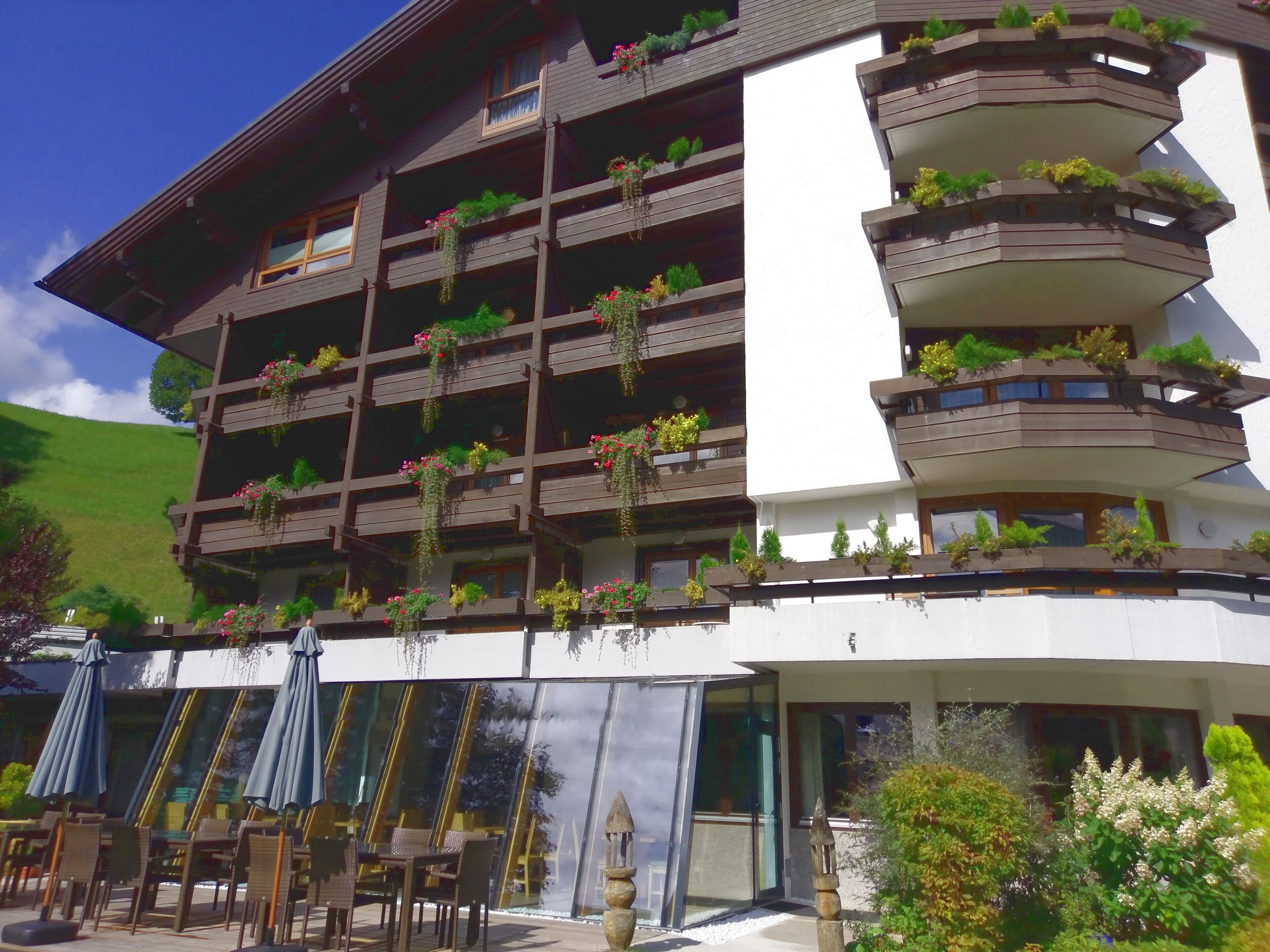 Een hotel met meerdere verdiepingen, voorzien van balkons met planten en bloemen.
