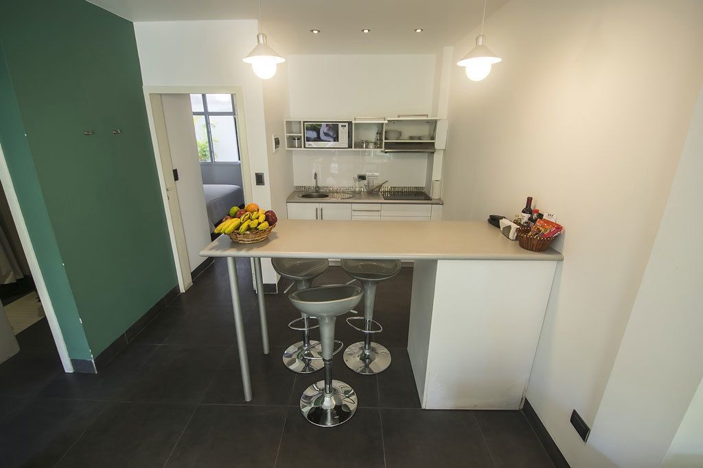 A modern kitchen with a central island, bar stools, and a fruit bowl.