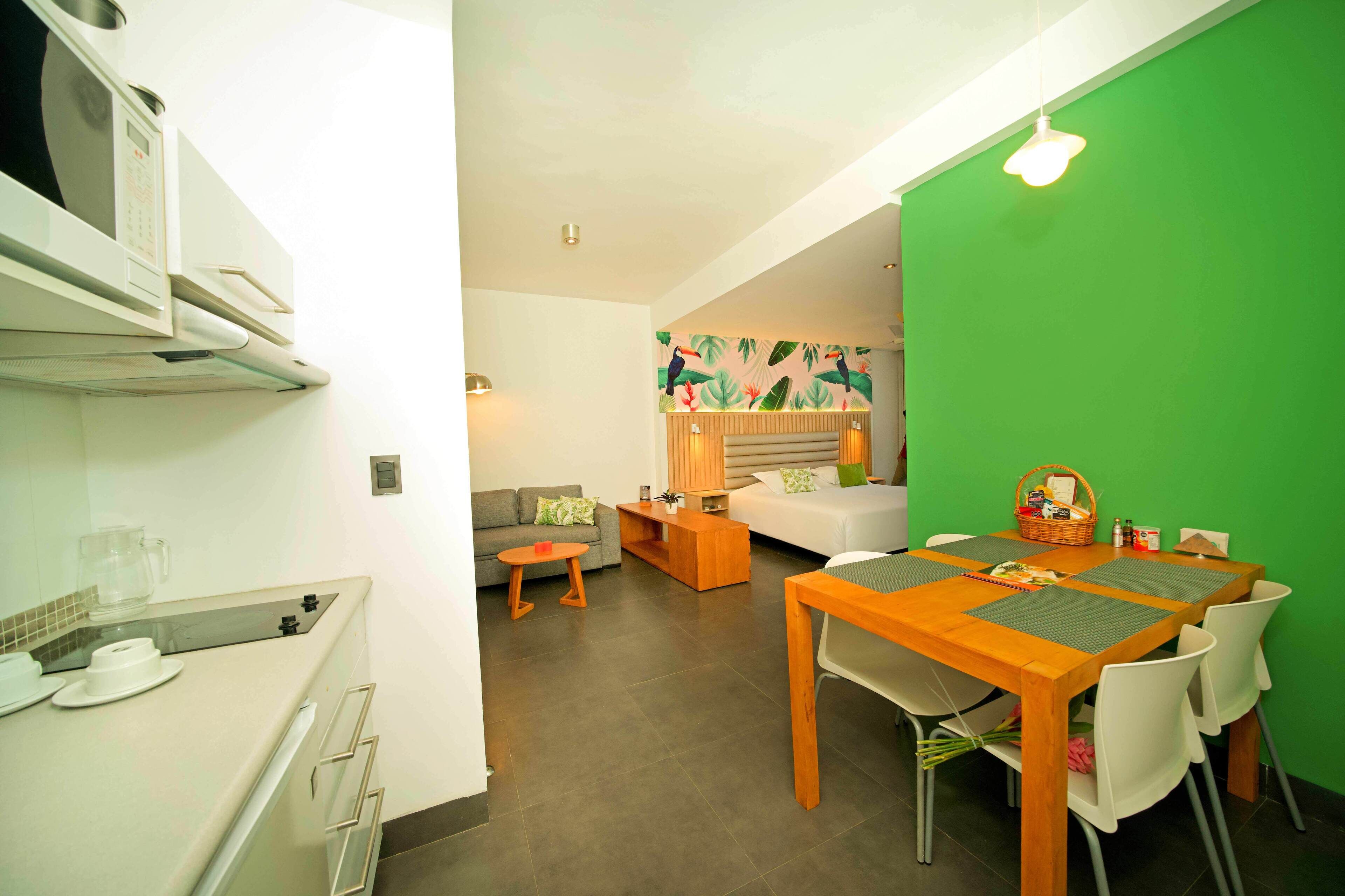 Un espacio habitable compacto con kitchenette, zona de comedor, sofá y cama.
