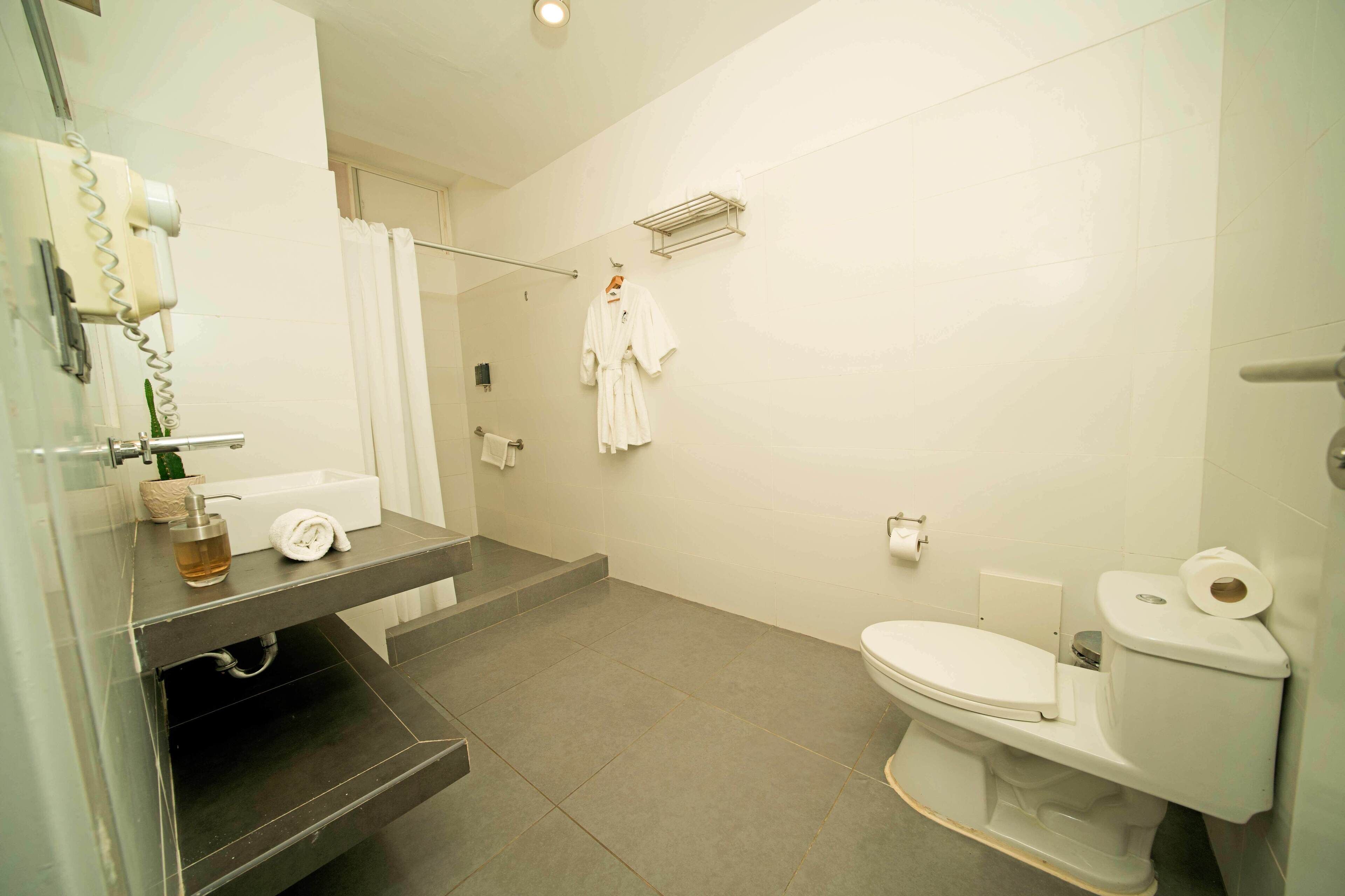 A bathroom with a toilet, a sink, a shower area, and a towel rack.