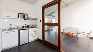 Cozinha moderna com micro-ondas embutido, lava-louças e porta de vidro deslizante para uma varanda com área de jantar.