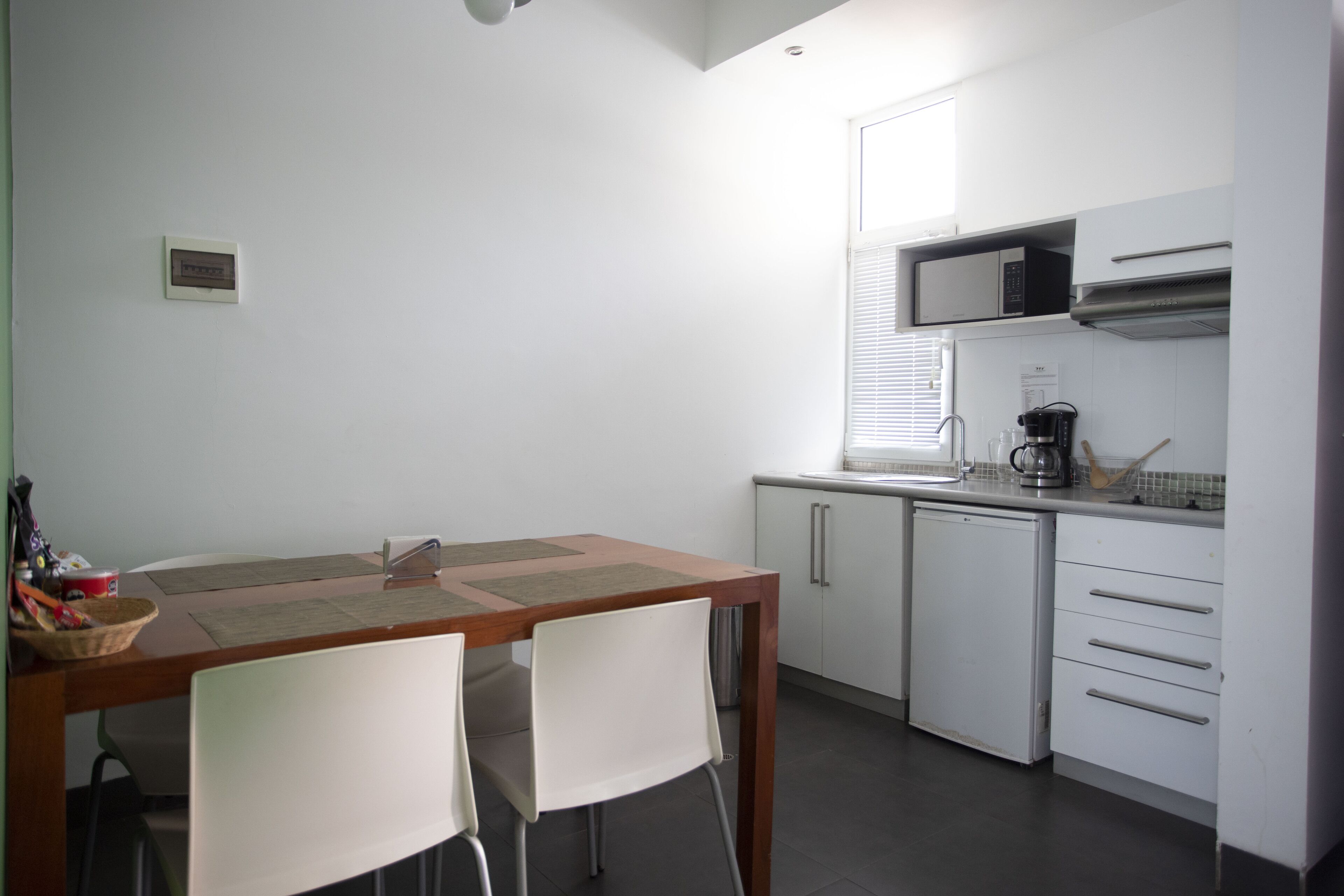 A compact kitchen with a dining table, chairs, a microwave, and a coffee maker.