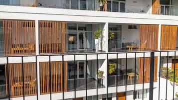 A multi-story building with balconies, wooden slats, and potted plants.