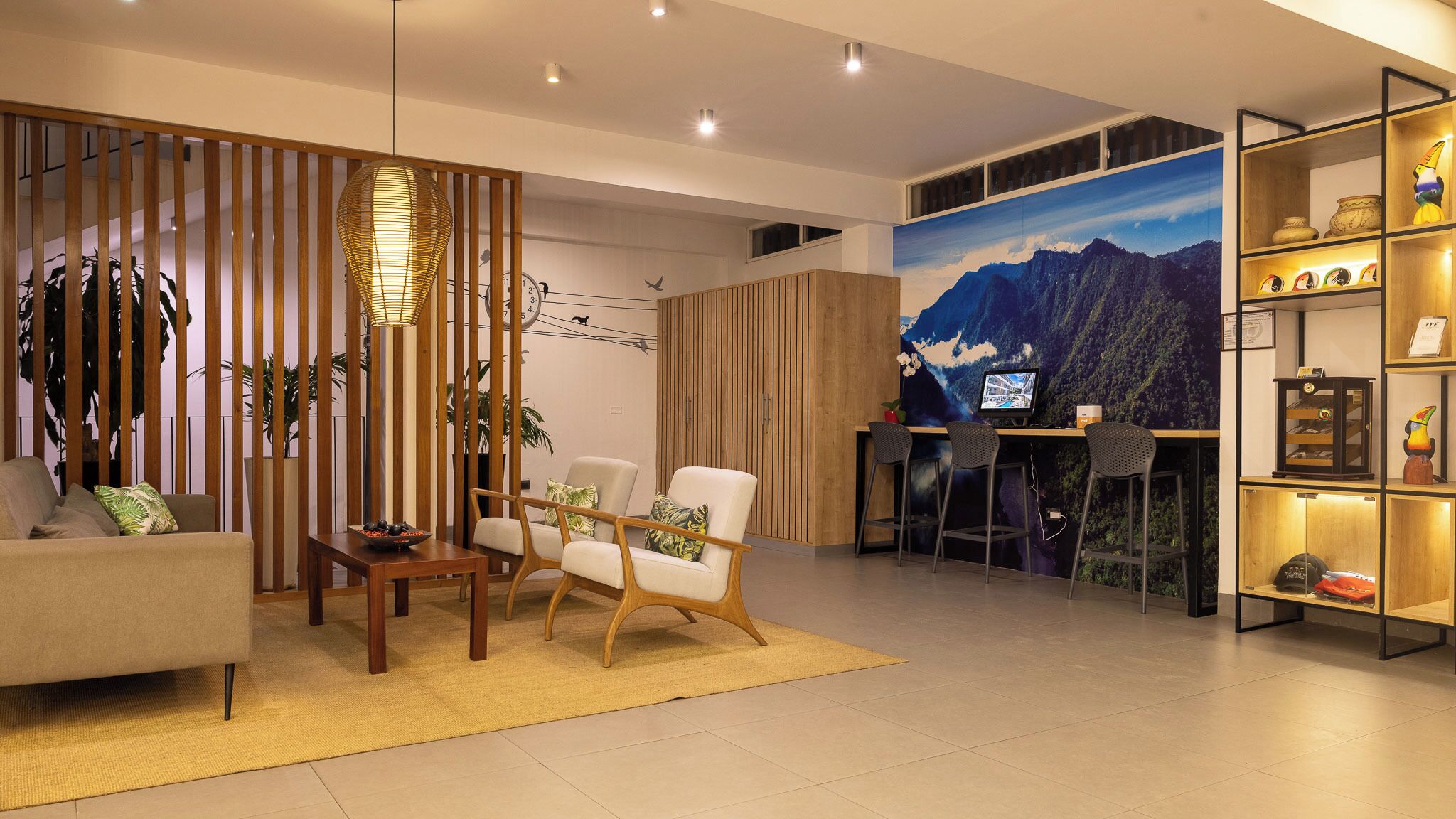 A modern living room with a sofa, two armchairs, a coffee table, and a decorative wall with a mountain painting.