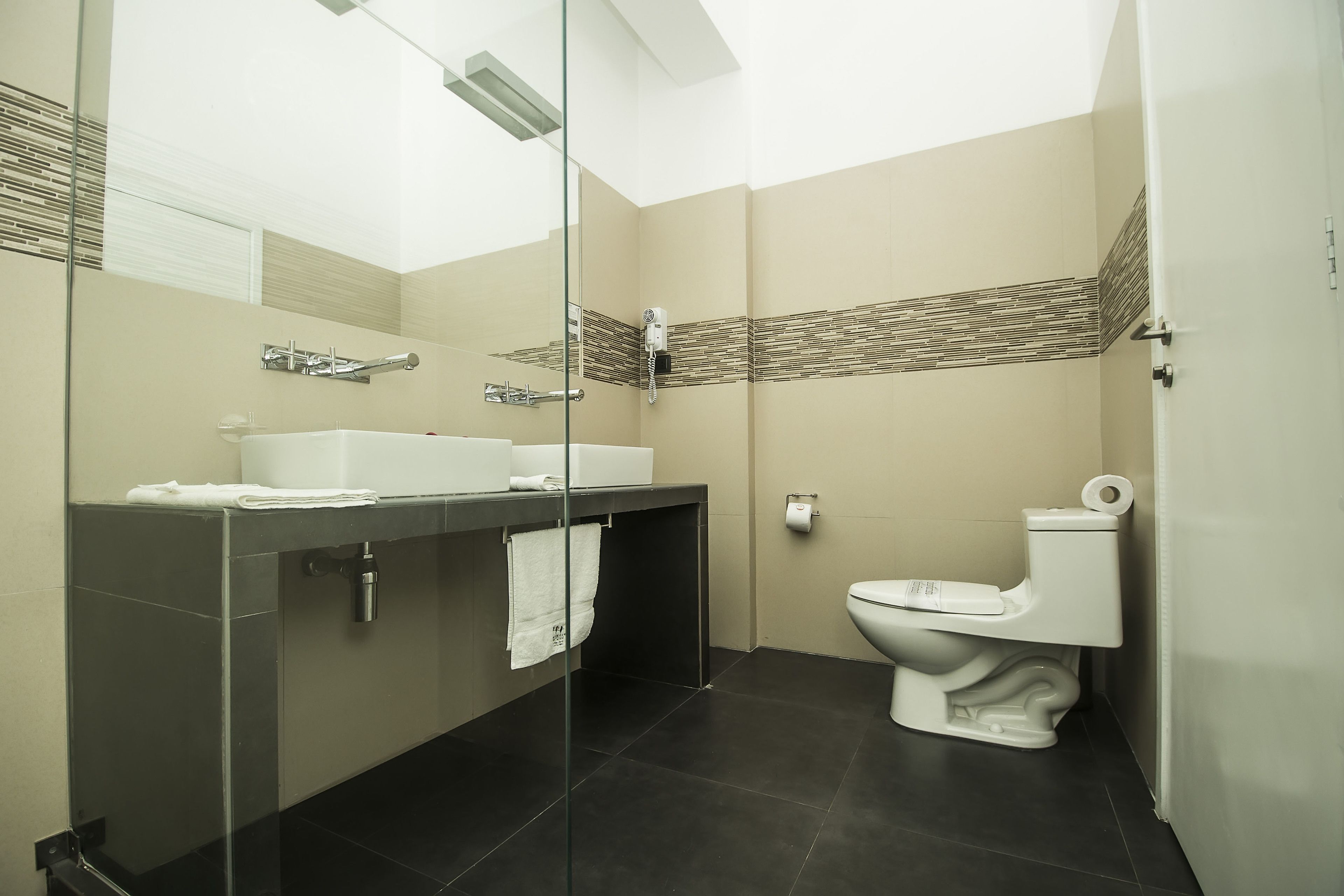 A modern bathroom with a glass-enclosed shower, a white sink, and a toilet.