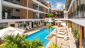 Um hotel moderno com piscina central, várias varandas e áreas de estar ao ar livre.