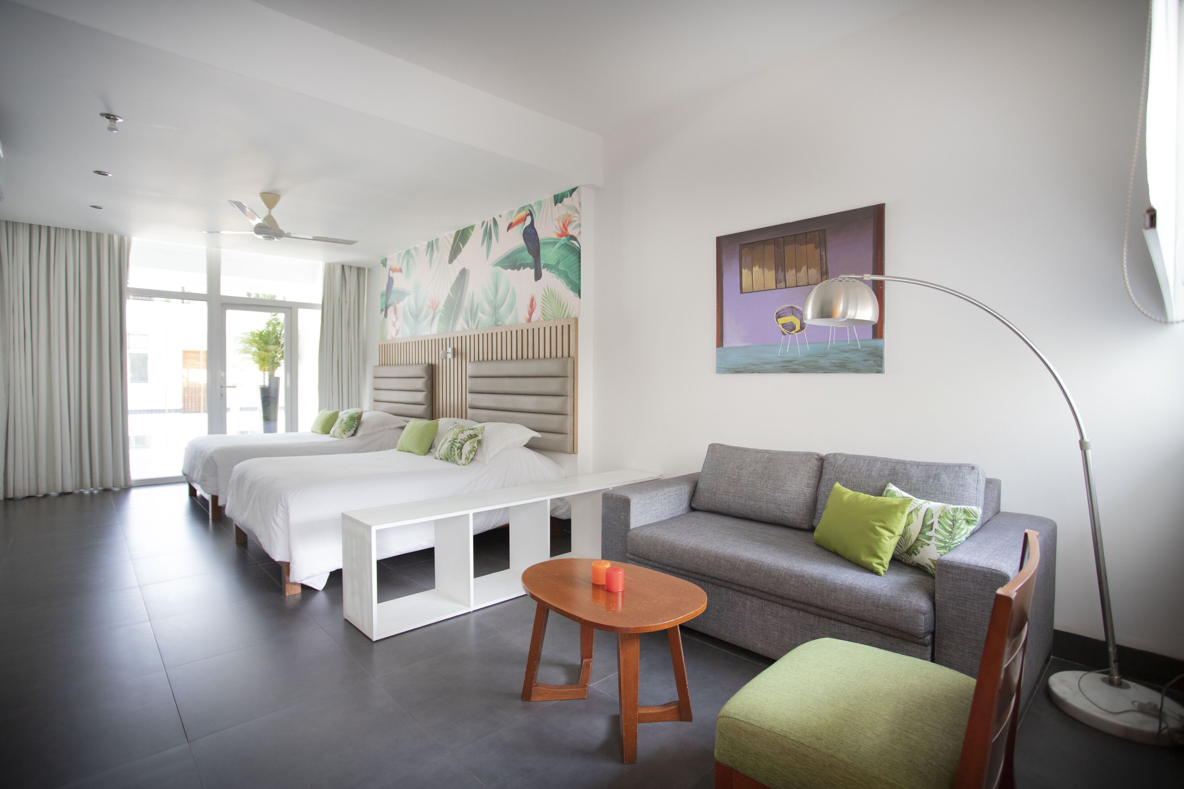 Een moderne hotelkamer met een groot bed, een bank, een klein tafeltje en een vloerlamp.