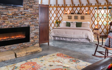 A yurt interior with a fireplace, bed, and a ceiling fan.