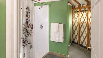 A bathroom with a shower, a towel rack, and a wooden lattice door.