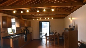 Una cocina compacta con armarios de madera, un comedor con mesa y sillas, y un sofá en la sala.