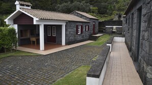 Un edificio de piedra con techo de tejas, un patio empedrado y un camino que lleva a una puerta.