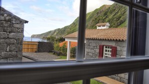 Un edificio de piedra con puerta roja, cerca de madera y vistas a un paisaje montañoso.