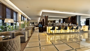 Un moderno vestíbulo de hotel con zona de bar, arreglos de asientos y piso pulido.
