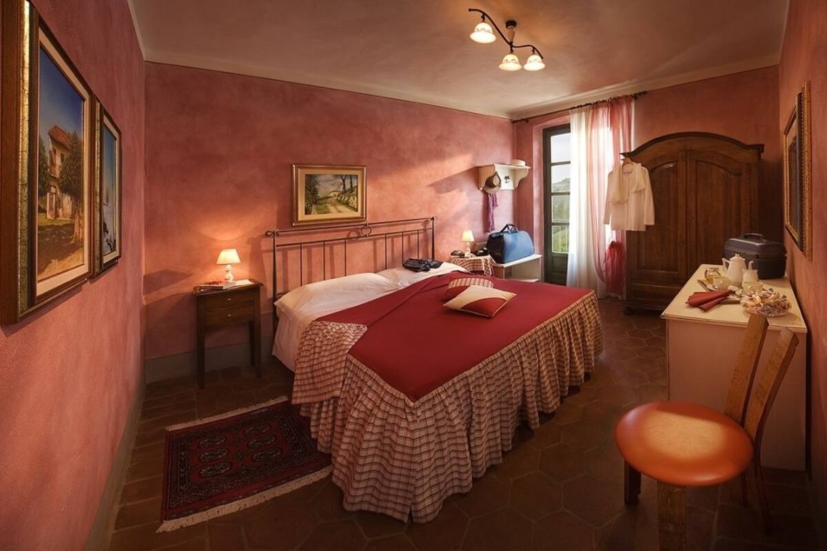 Un dormitorio con una cama grande, una mesita de noche con lámpara, un aparador y una silla.