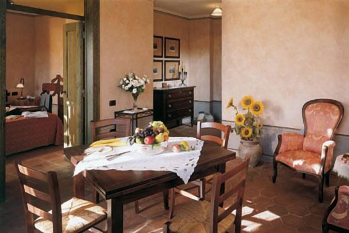 Un comedor con una mesa de madera, sillas y un jarrón con girasoles.