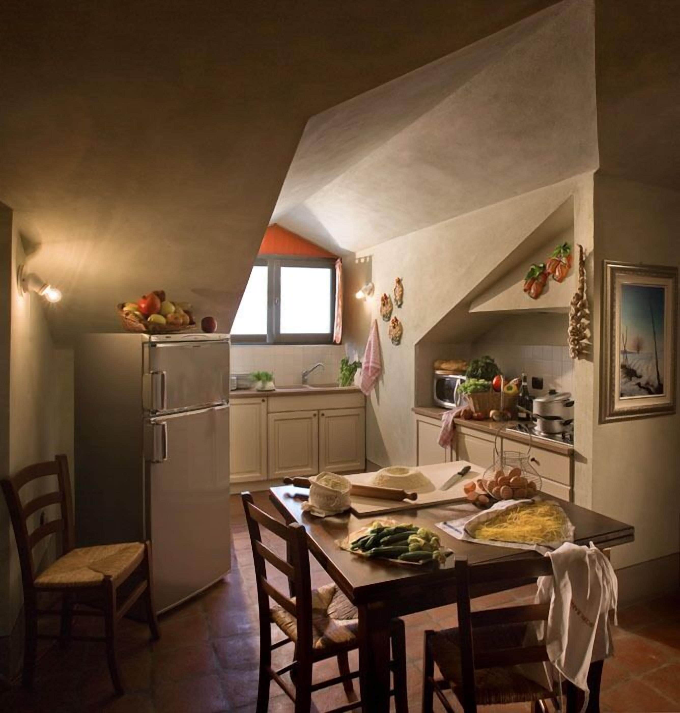 Une cuisine de taille réduite comprenant un réfrigérateur, une table à manger avec des chaises et une fenêtre.