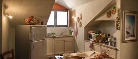 Una cocina compacta con refrigerador, una mesa de comedor con sillas y una ventana.