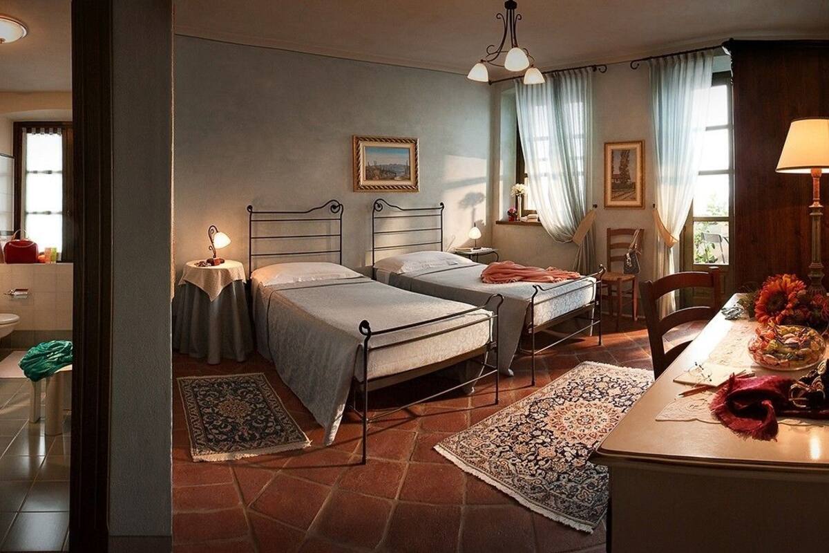 Habitación de hotel con dos camas, zona de estar con una mesa, vista a la ciudad y baño.