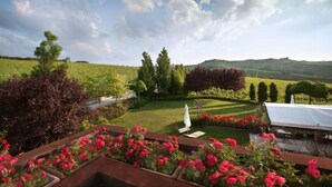Un jardín ajardinado con césped, una sombrilla blanca y un banco.