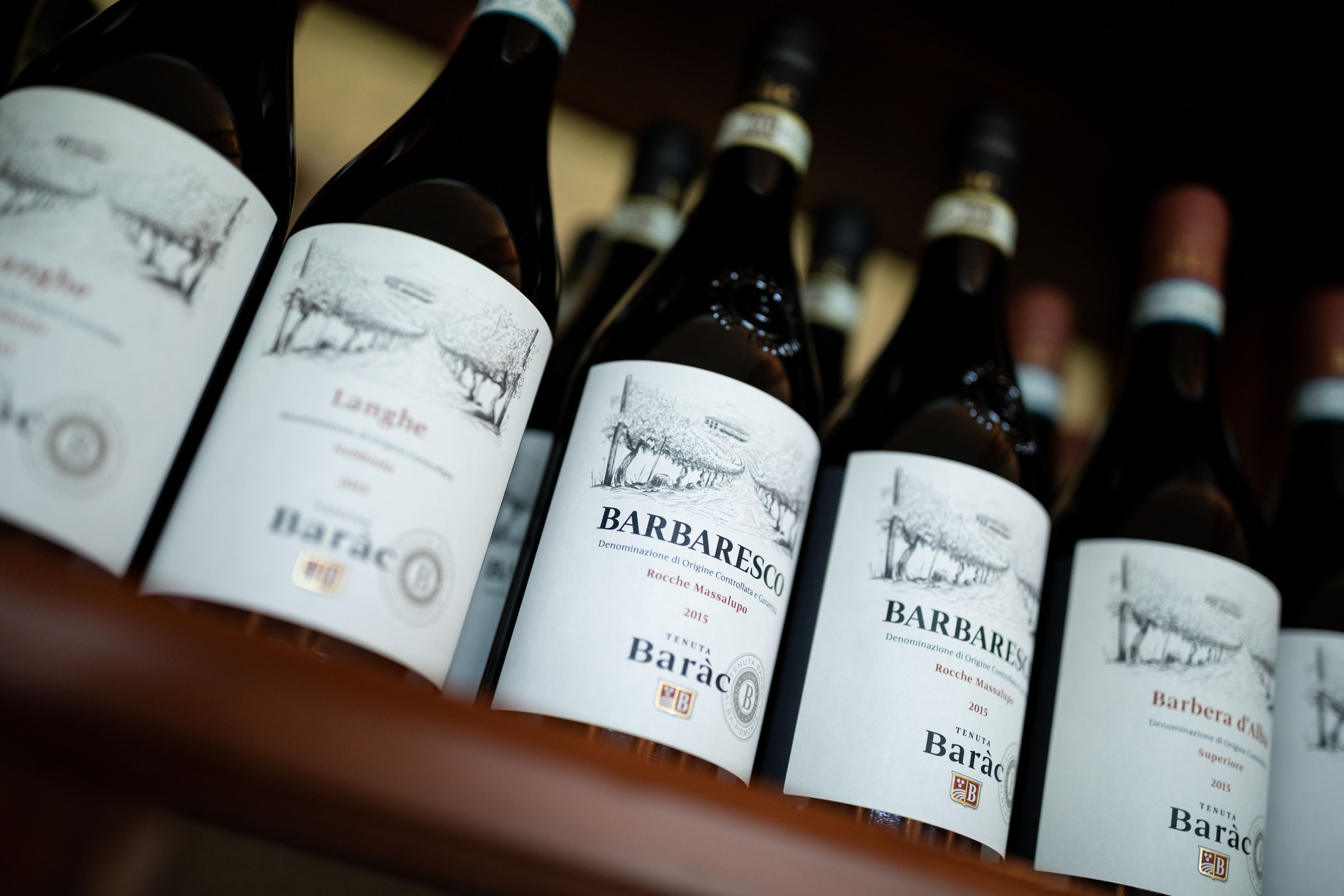 Una hilera de botellas de vino con etiquetas, cada una con un diseño y texto similares.