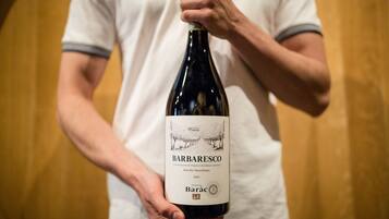A person holding a wine bottle labeled "Barbaresco" with a detailed label.