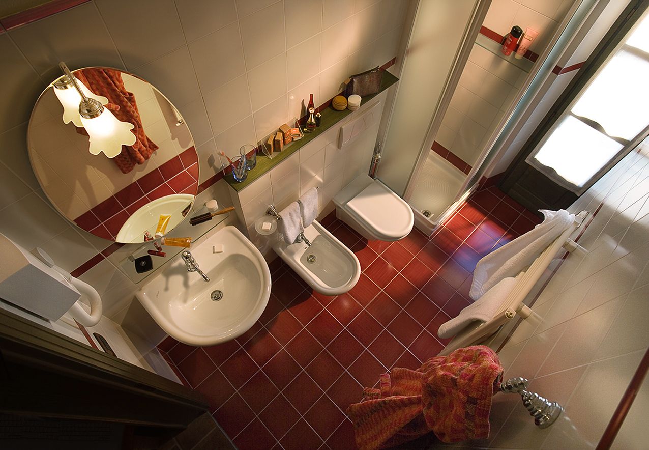 Une salle de bain équipée d’un lavabo, d’un bidet et de toilettes. Un miroir se trouve au-dessus du lavabo et un porte-serviettes est placé à côté des toilettes.