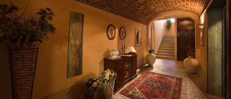 A hallway with a brick ceiling, a rug, a cabinet, and a staircase.