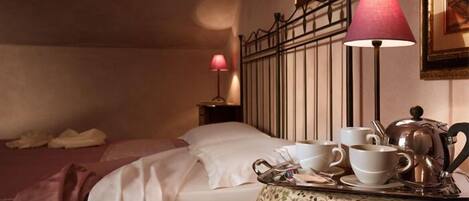 Une chambre d’hôtel avec un lit, une table de chevet avec une lampe et une table avec un service à thé.