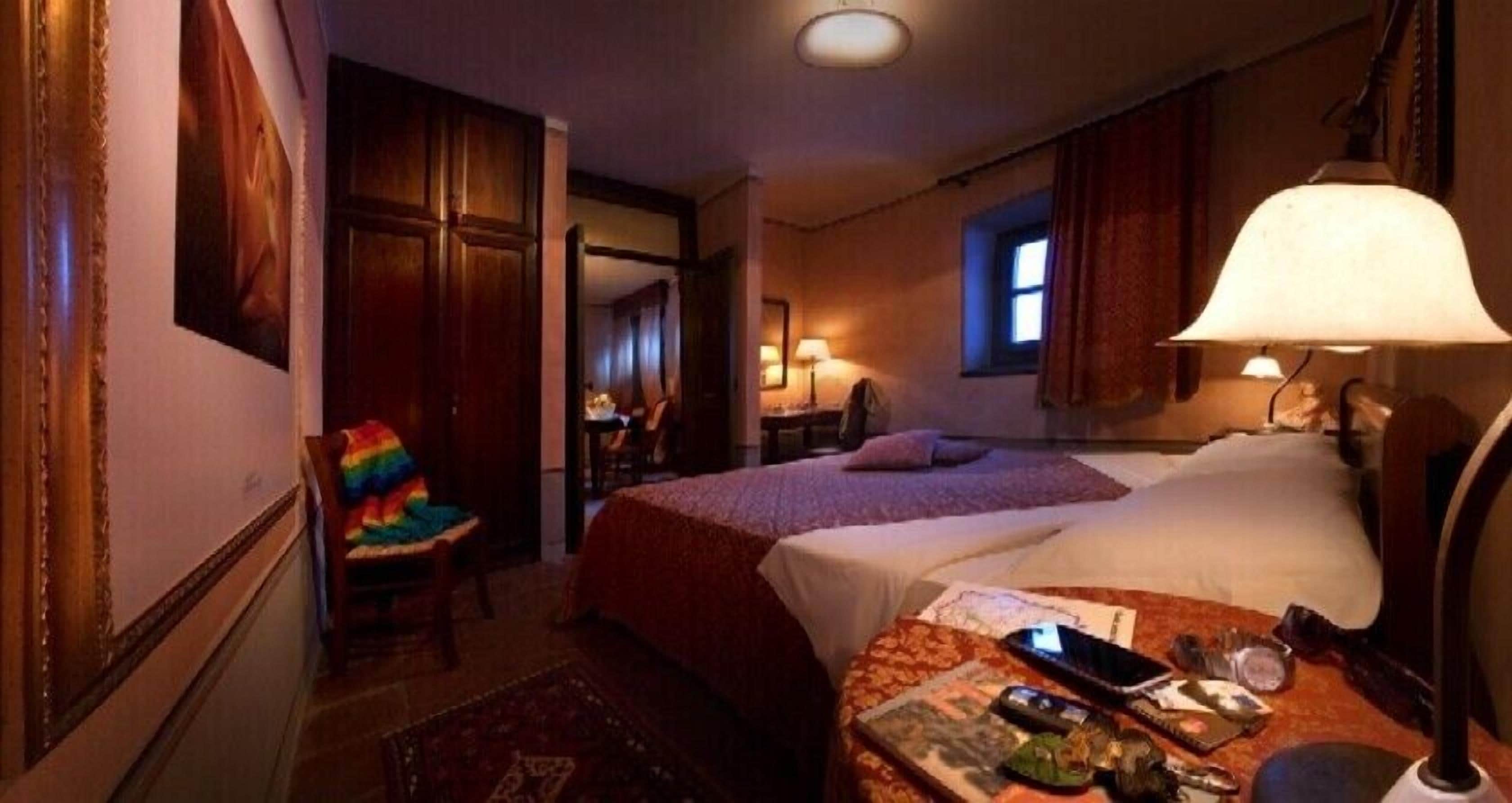 Una habitación de hotel con dos camas, un escritorio, una silla y una lámpara.