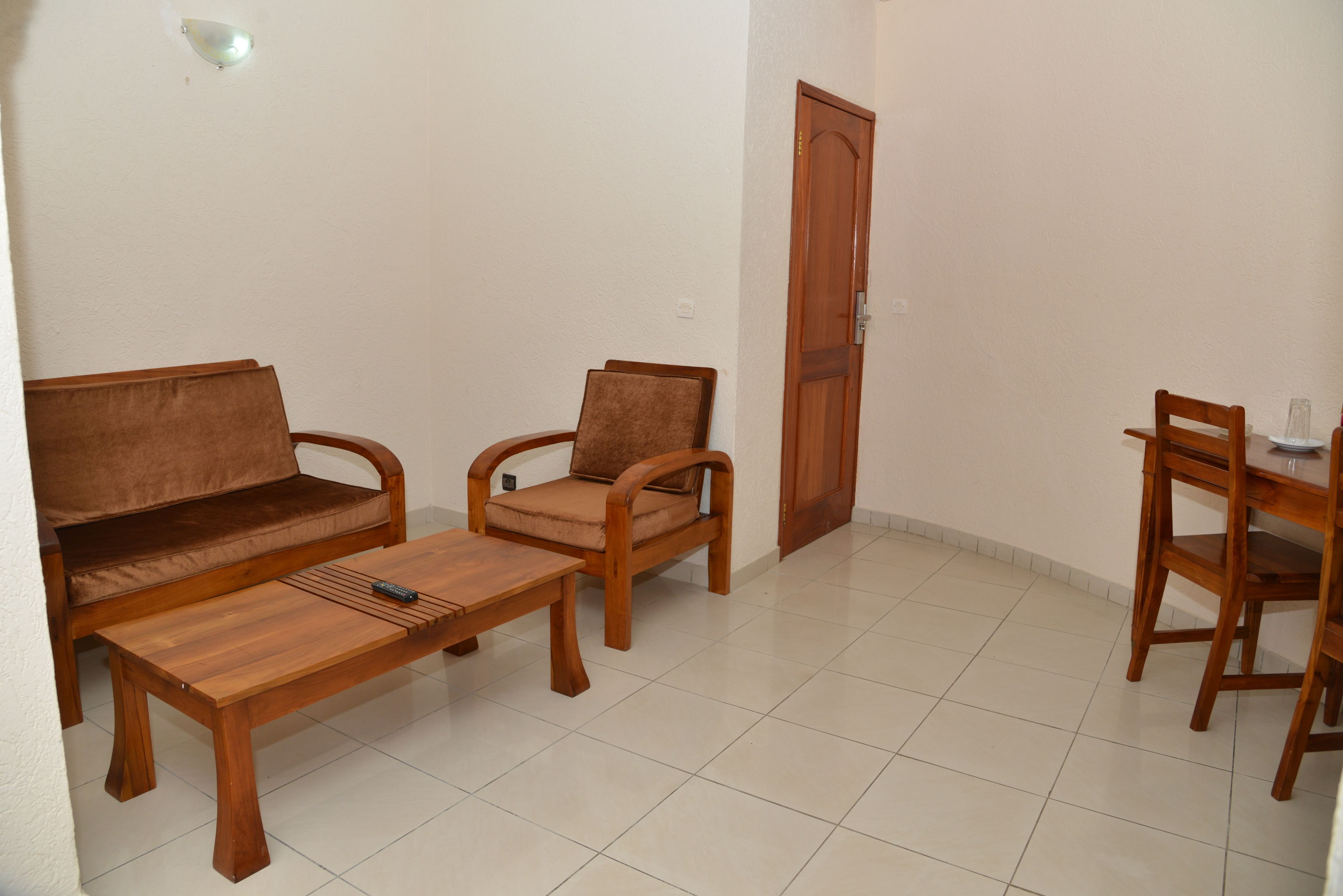 A living room with a sofa, two armchairs, a coffee table, and a dining table with chairs.
