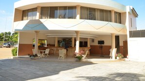 Un hôtel doté d’une façade incurvée, d’un espace extérieur abrité avec des chaises et des tables, et d’un bar.
