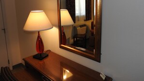 Habitación de hotel con escritorio de madera, lámpara, espejo y cartel que indica el tipo de habitación.