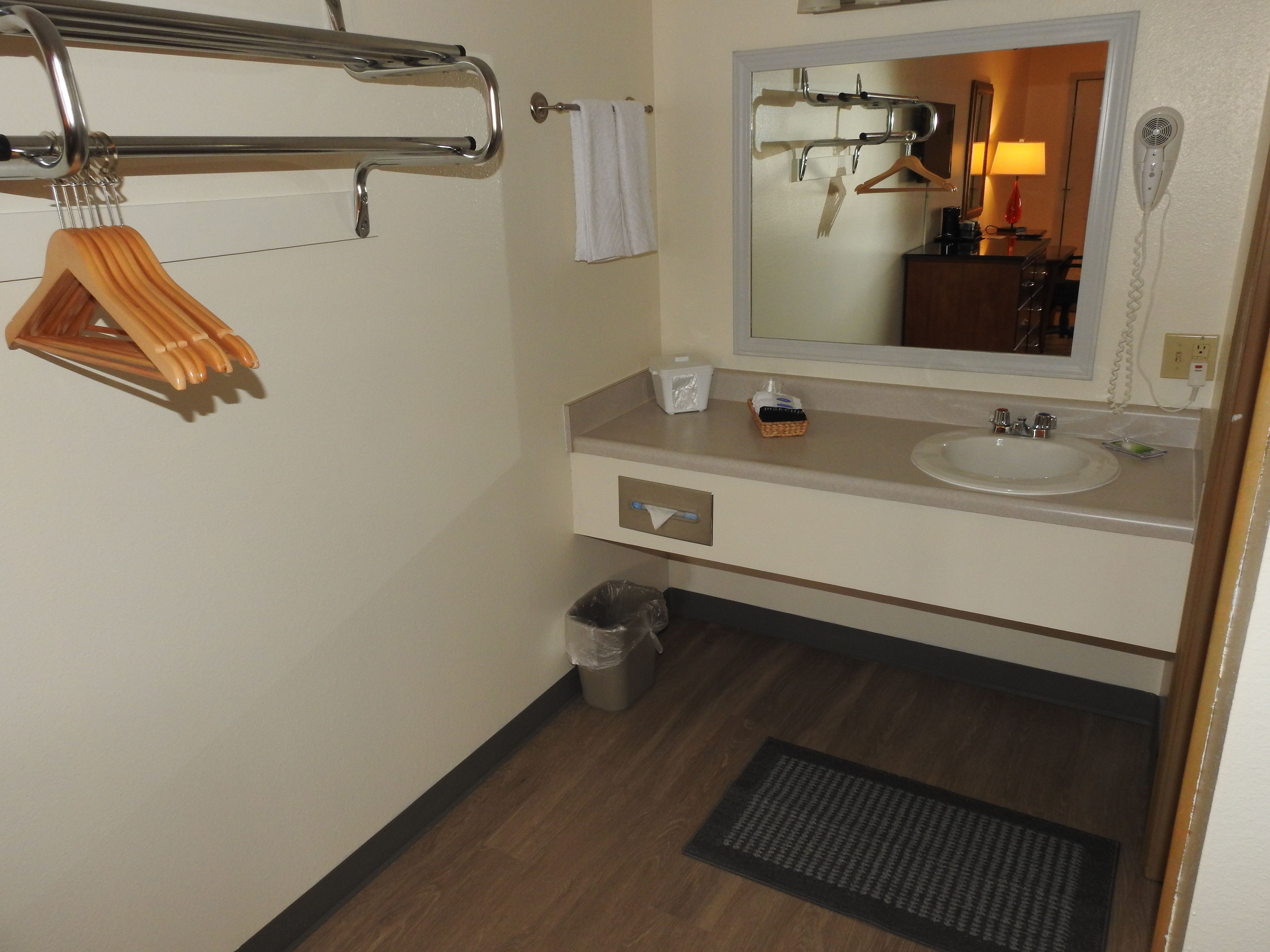 A bathroom with a sink, mirror, towel rack, and a trash bin.