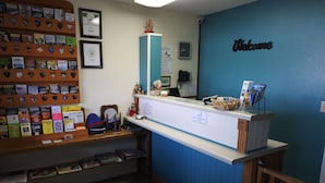 Un mostrador de recepción con una pared azul, un letrero que dice 'Welcome', un reloj y un teléfono.