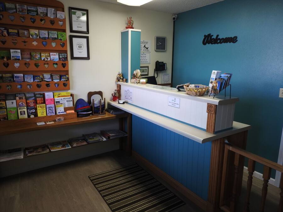 A reception desk with a blue wall, a 'Welcome' sign, a clock, and a phone.