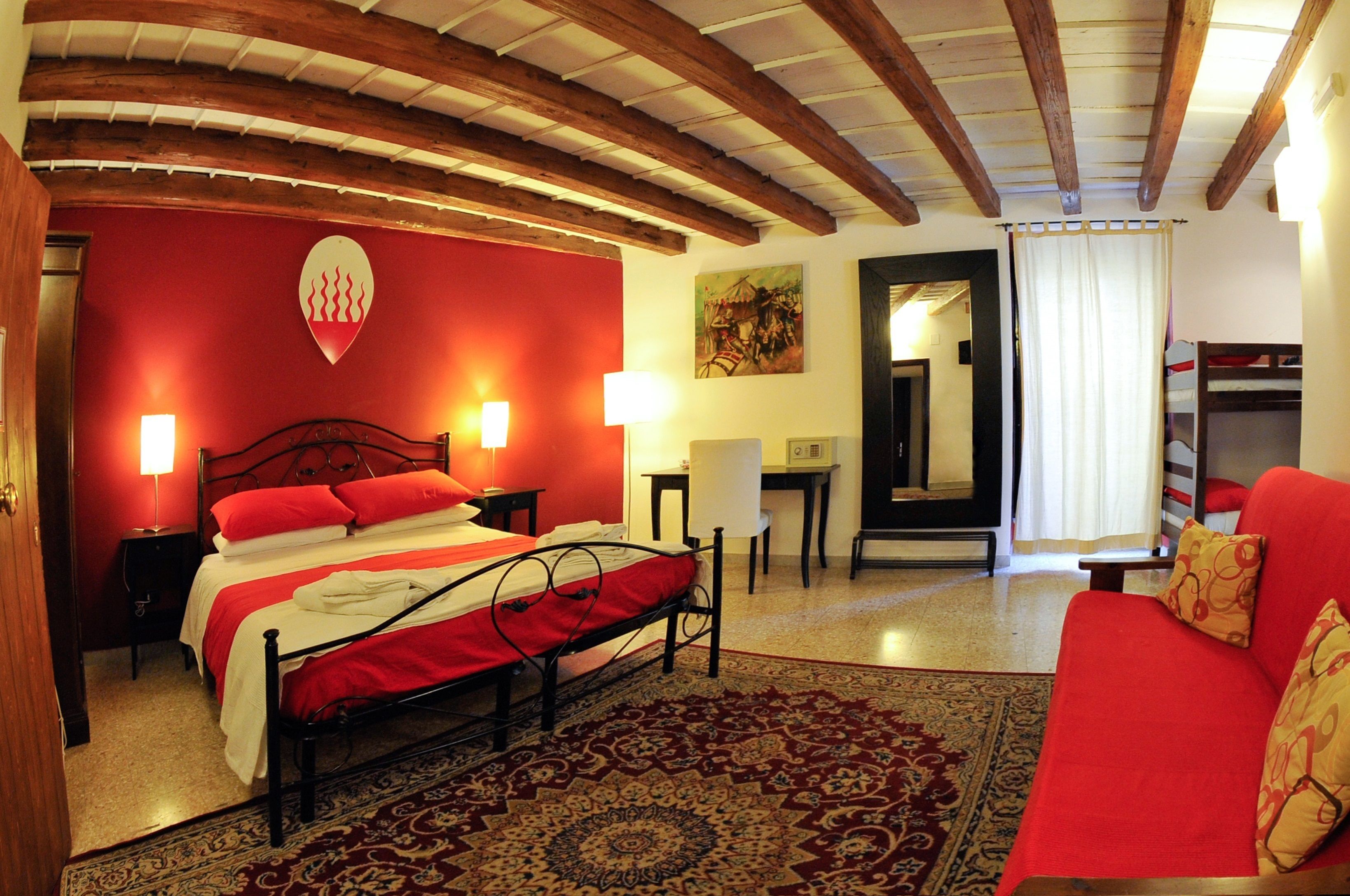 Ein Hotelzimmer mit einem Bett, einem roten Sofa, einem Schreibtisch und einem Spiegel.